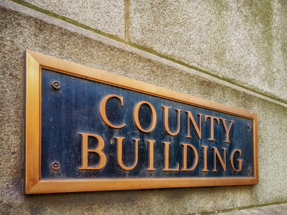Exterior,Sign,That,Reads,"county,Building",In,Brass,Lettering.,Graphic