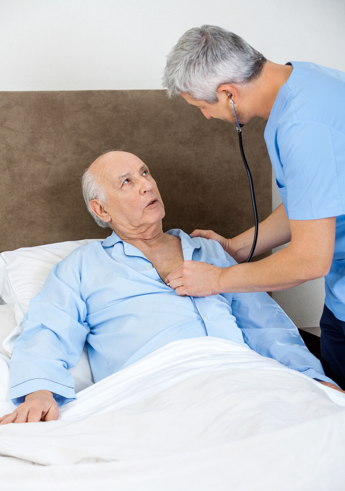 Male,Caretaker,Examining,Senior,Man,With,Stethoscope,In,Bedroom,At